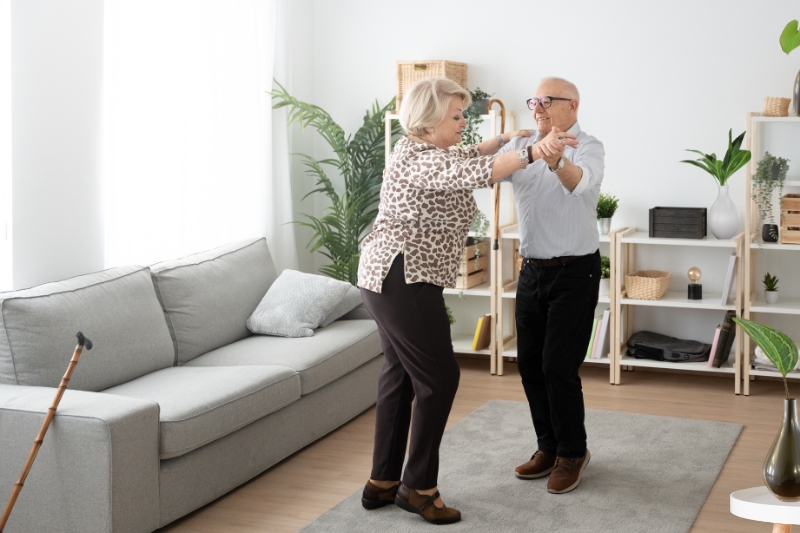 old couple dancing in their living room with preserved plants